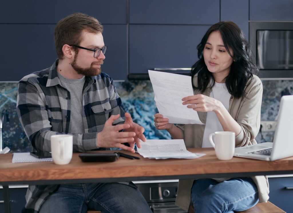 pexels photo 6963033 Young couple managing their finances with laptop and documents in a modern kitchen setting.